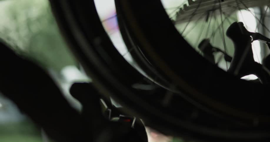 A bicycle wheel spins on a rack as a man steps out and closes the door