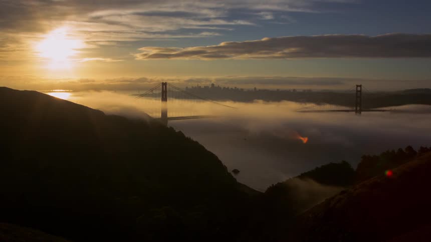 Clouds roll low over hills and a bridge