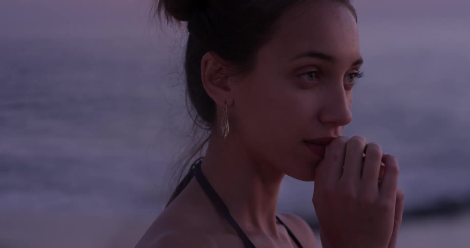 A woman turns and presses her hands to her face