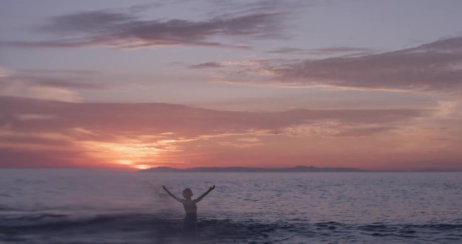 Woman stretches on the beach as the sun sets