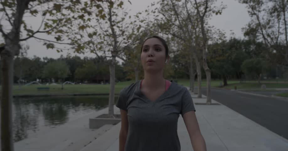 Woman walks past between pond and street and stretches