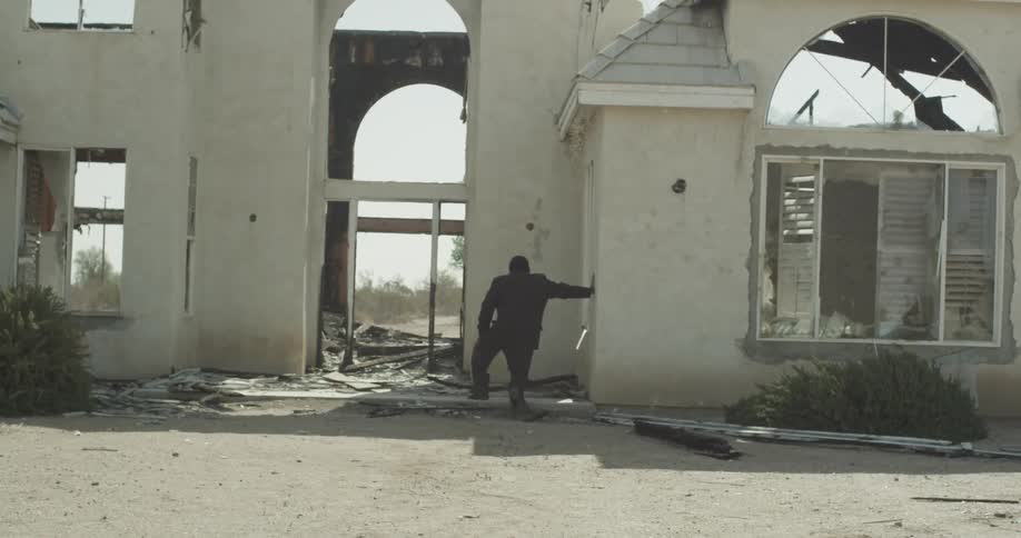A man falls down beside a broken down building
