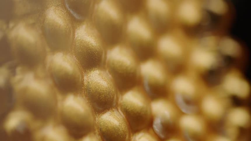 A light shines on a golden bumpy surface