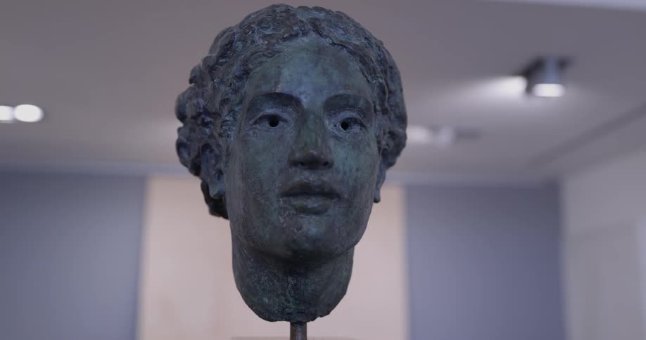 A bust sits under a white ceiling with lights in it