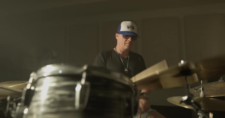 Man wearing baseball cap  plays drums
