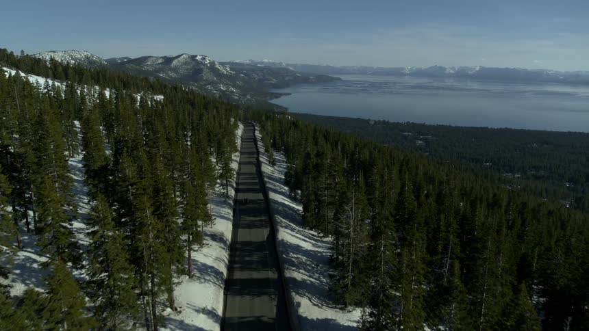 Cars drive along a highway on a mountain that is surrounded by a forest