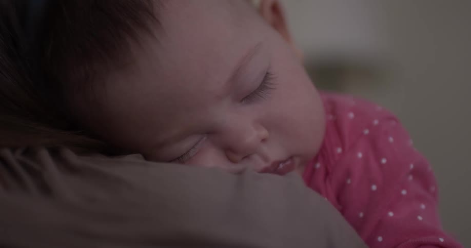 A baby sleeps on someone's shoulder