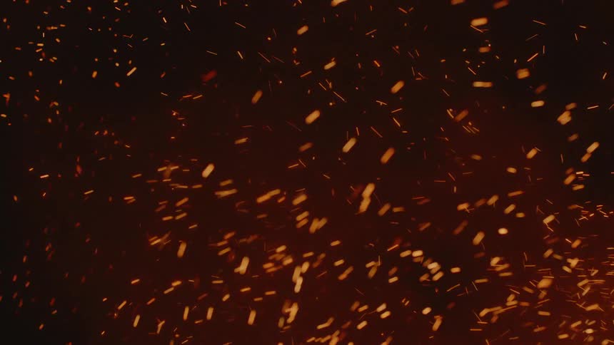 Embers and sparks floating through the air near a flame