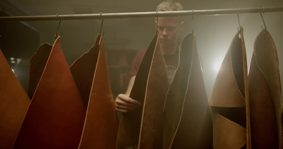 Man inspects hanging pieces of leather
