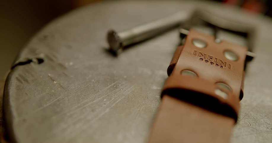 Brown leather belt on wooden table with bolt nearby