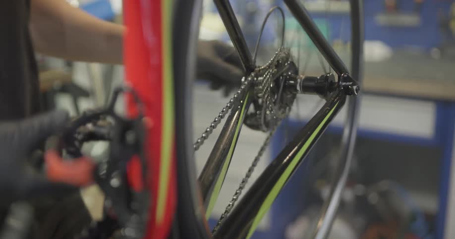 A man is working on a bike then he spins the bike wheel