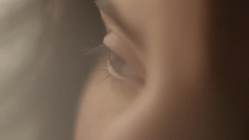 A woman opens her eye as the wind blows her hair
