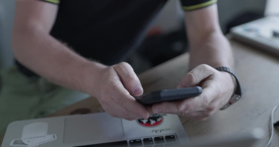 Man rests against a table while texting
