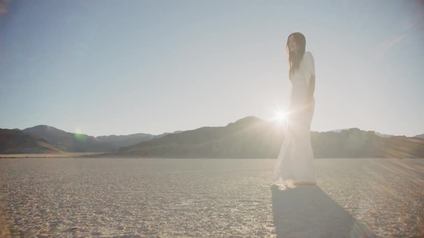 Woman walking in a dry lake bed in a white dress