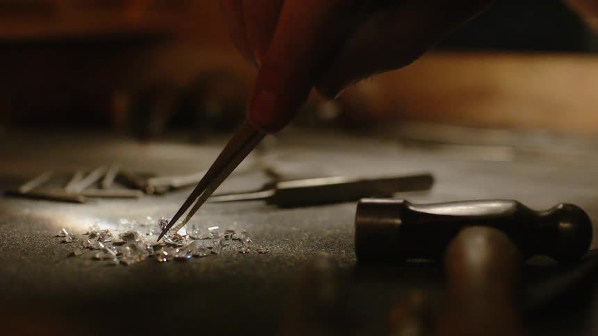 Someone is picking up diamonds with a tweezer