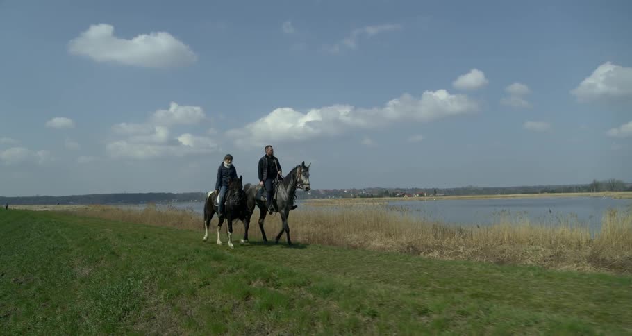 Two people are riding horses outside