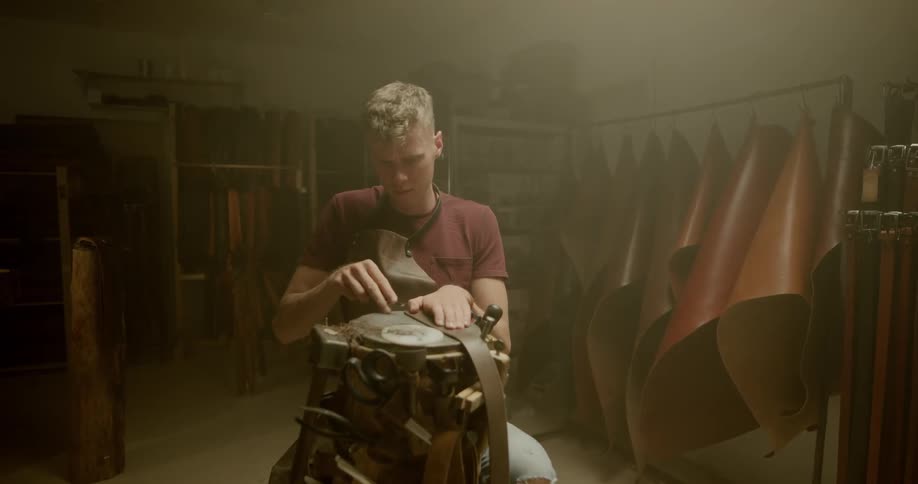 A man is cutting pieces of leather