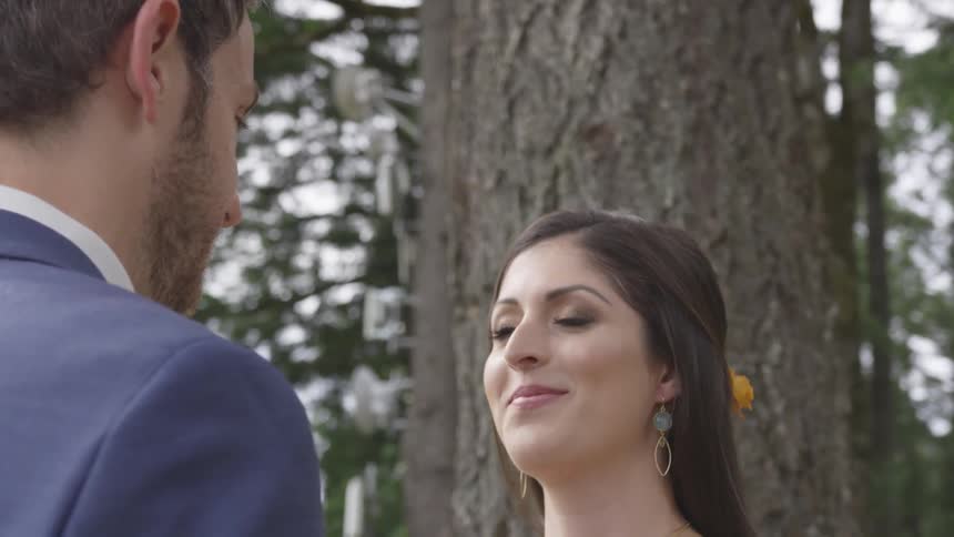 A man and woman face each other outside near trees