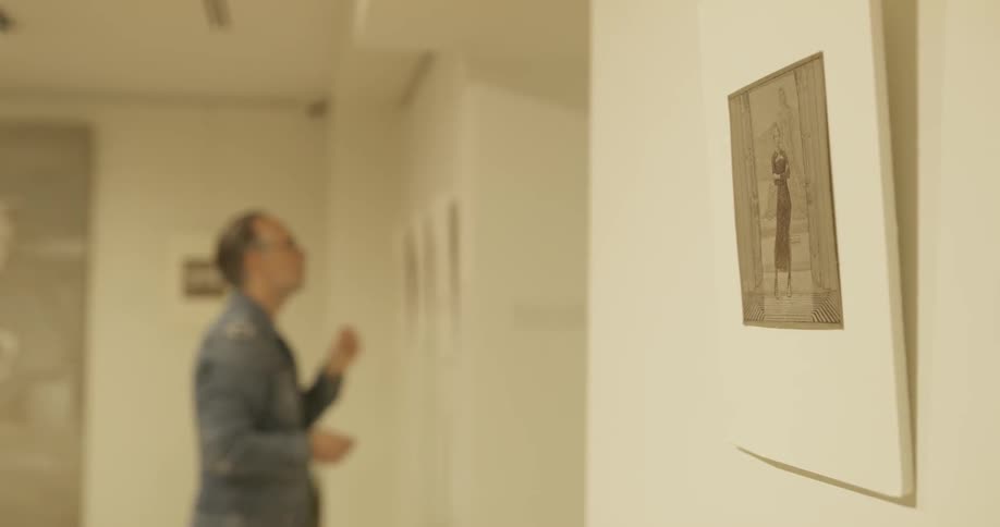 A man is looking at paintings in a room