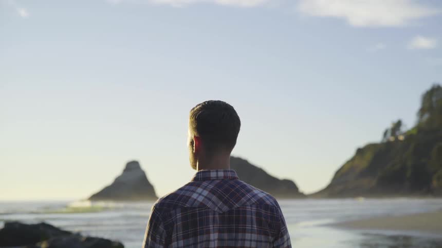 A man looking at the ocean from the beach