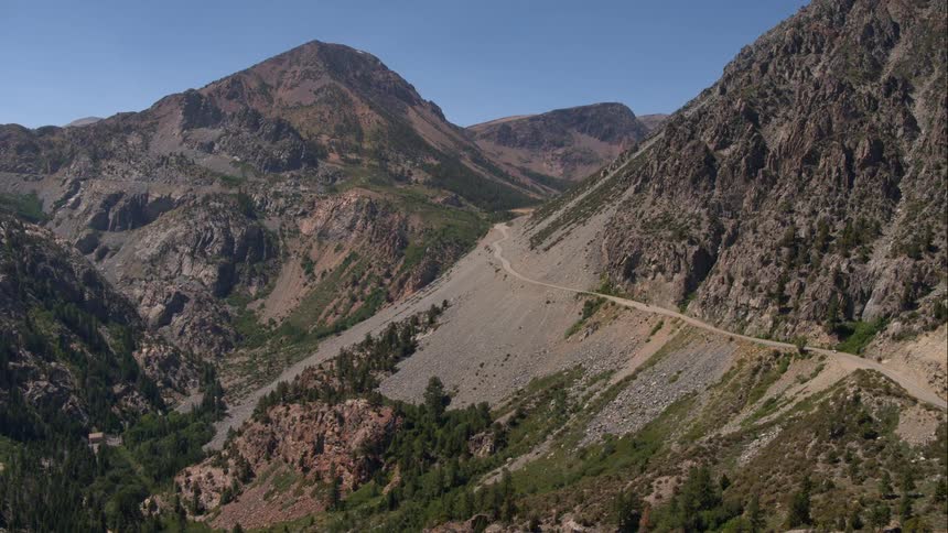 A dirt road winds around a tall mountain