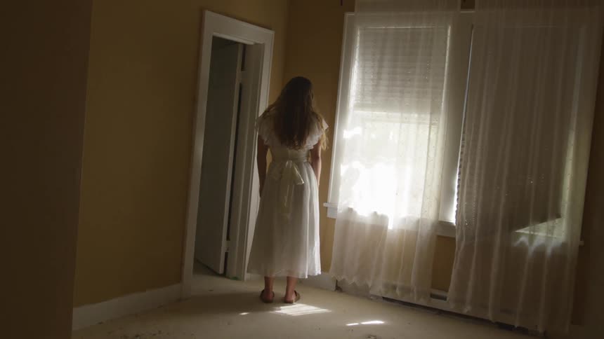 Woman stands in room facing corner