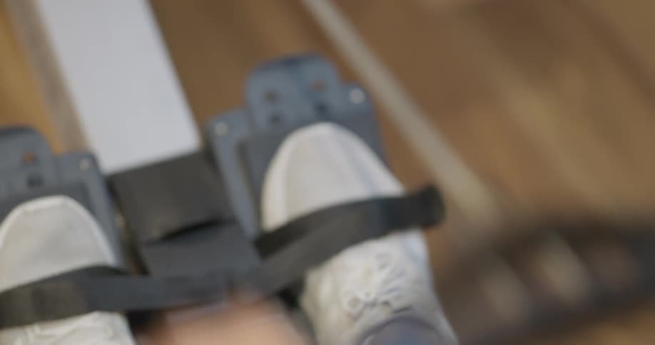A man slips his feet into straps and starts using a rowing machine