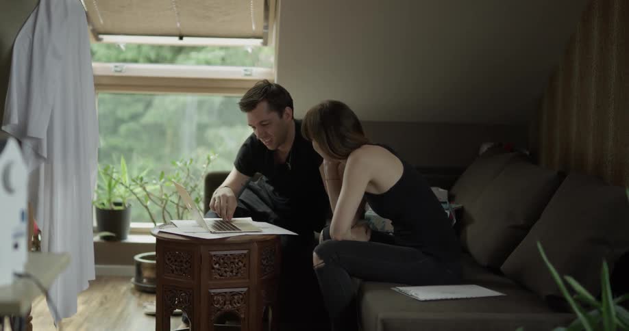 A man and a woman laughing together sitting on a couch