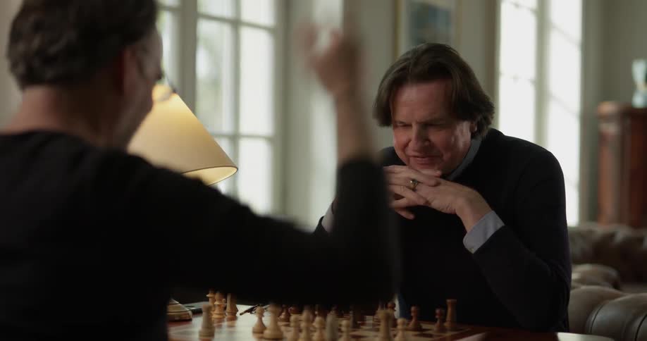 Two men have a conversation while playing chess