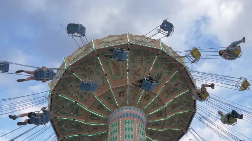 People ride a huge rotating swing at a theme park