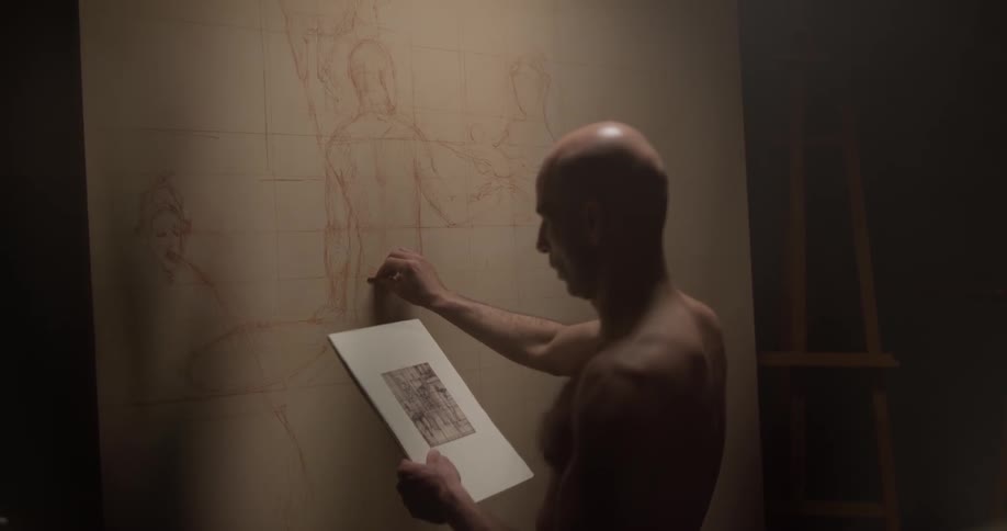 Man sketches on a large piece of paper on the wall