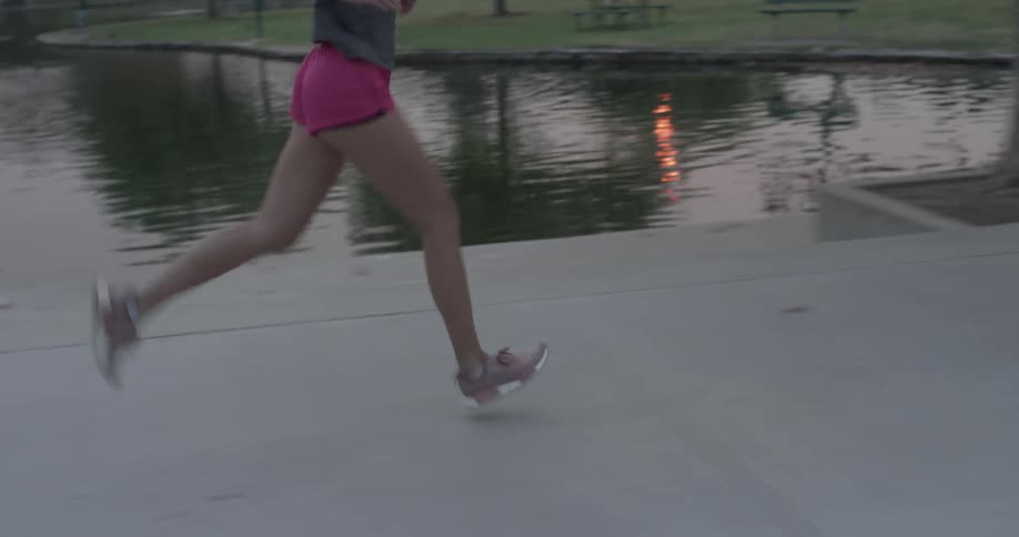 A woman runs along a path besides a body of water