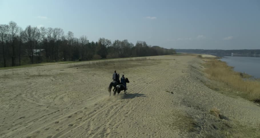 Two horses galloping through a pasture of open land