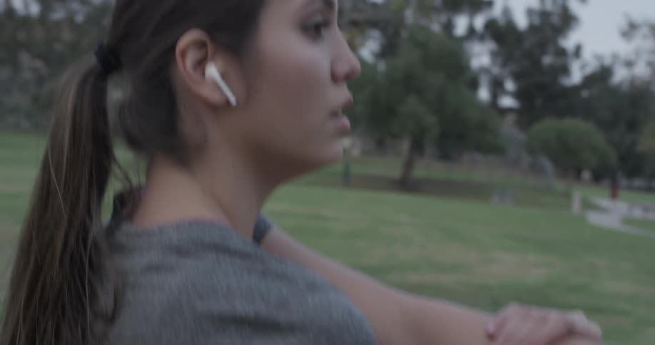 Woman puts in headphones before stretching out while watching