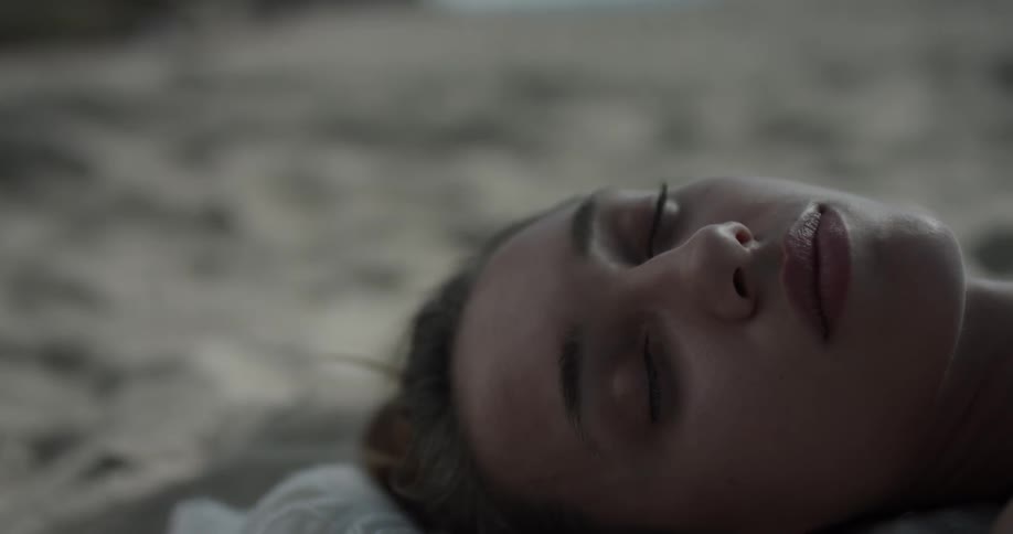 A woman is laying down with her eyes closes inside a home on the floor