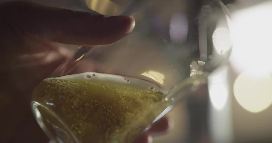 Person holds a glass up to a tap and beer pours in