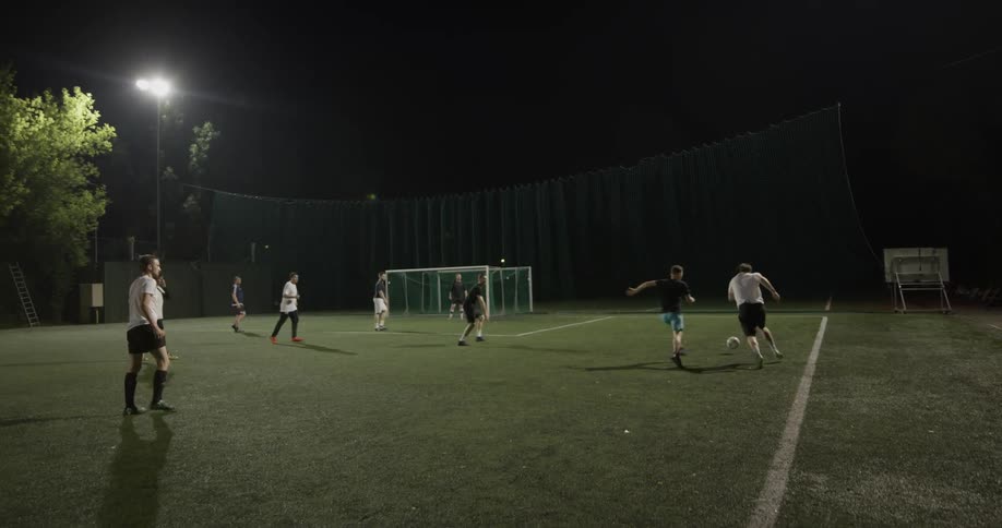 A group of men playing soccer at night
