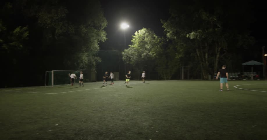 People playing soccer at night on a grass field