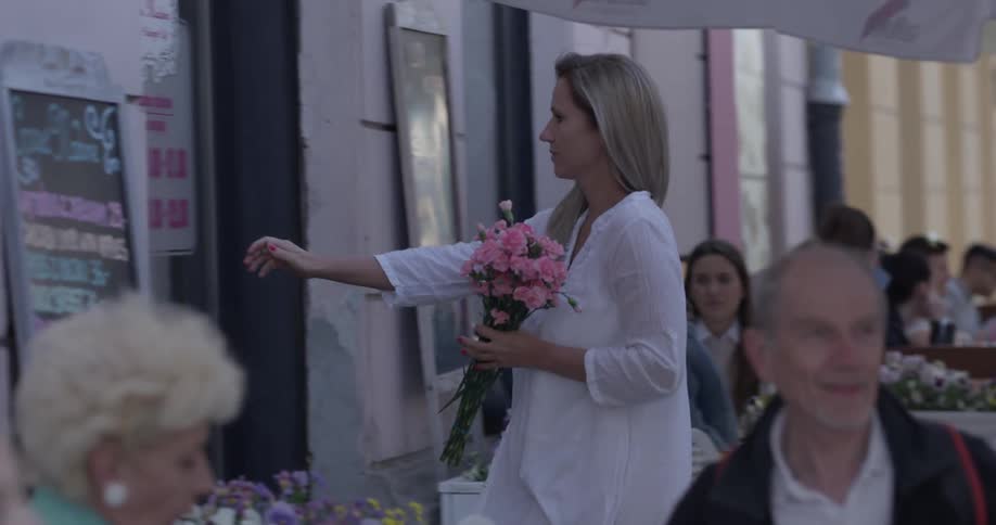 A woman is holding flowers and walks in a store