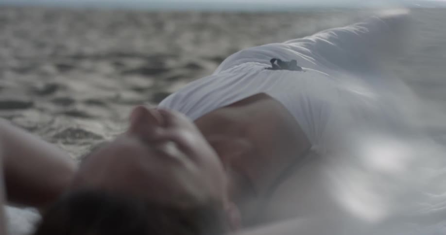 Woman in white dress lays in sand