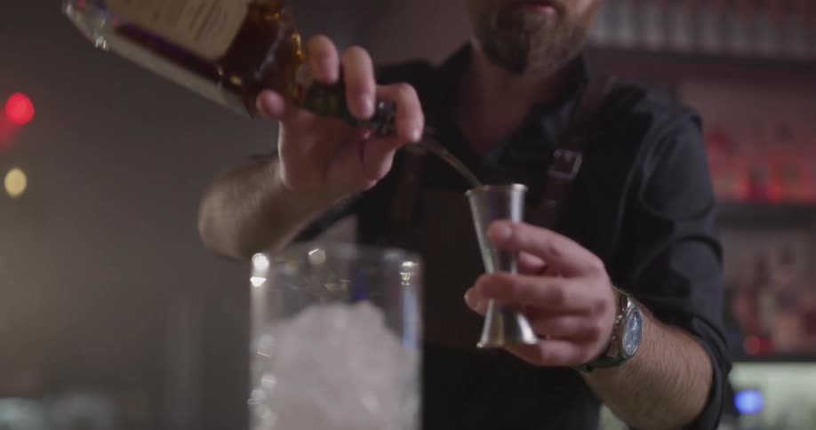 A person pouring liquor into a measuring cup