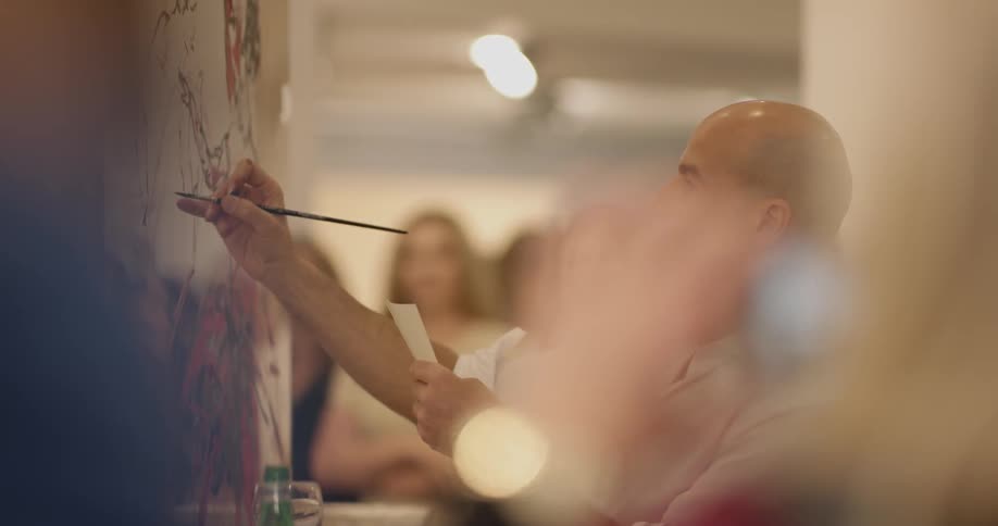 A man paints on a wall while watched by a crowd