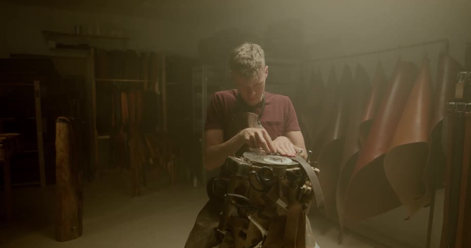 A man in a leather workshop making a leather strap