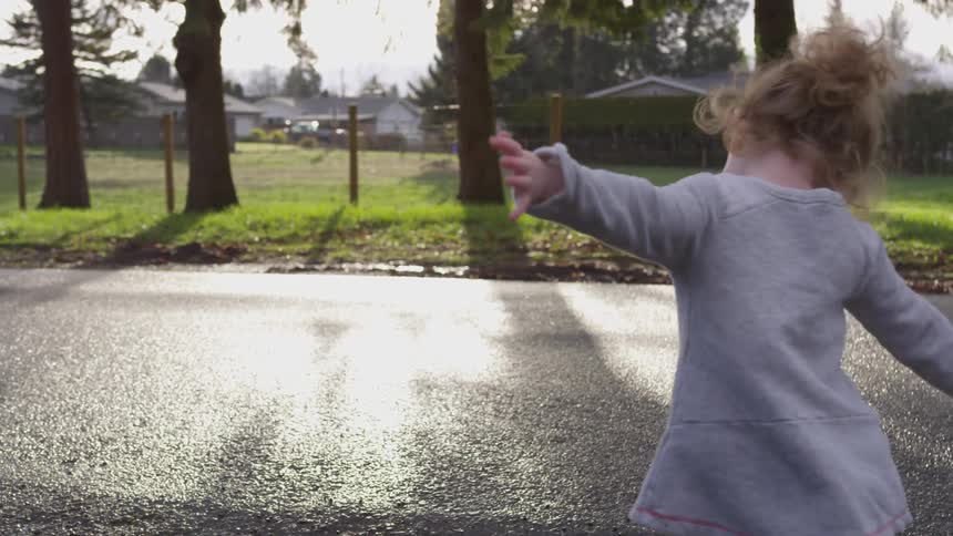 A young child dances in a driveway