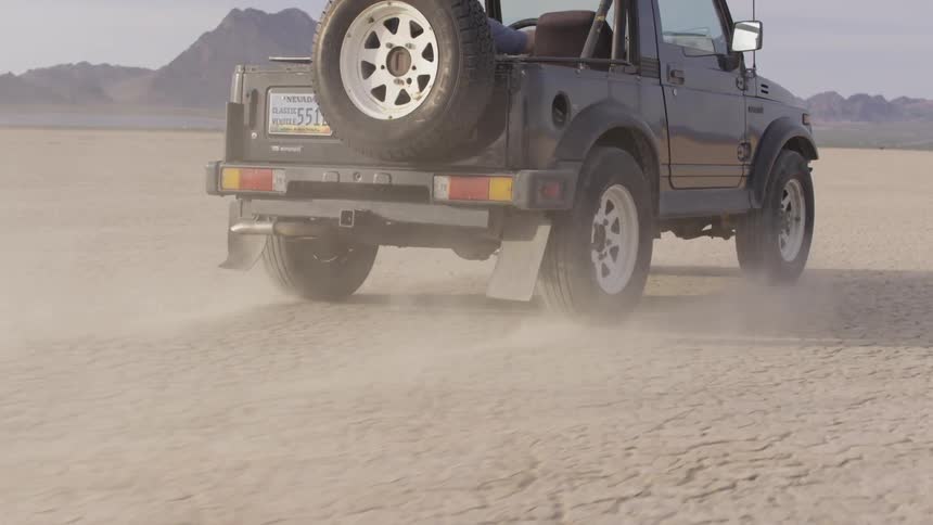 A jeep drives over the dry dirt ground