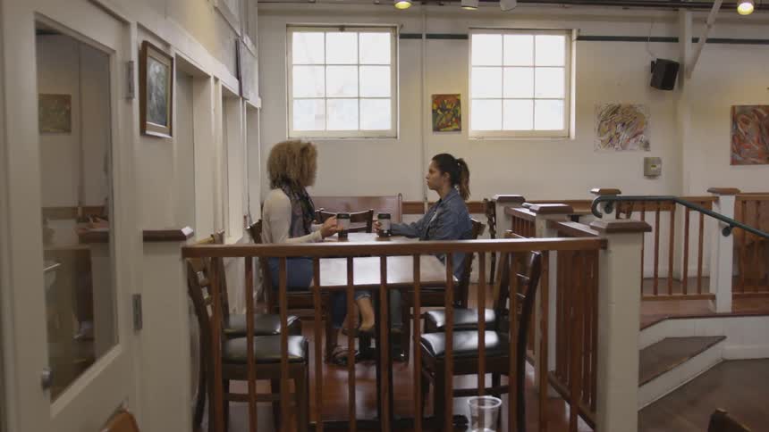 Two women sit at table and talk