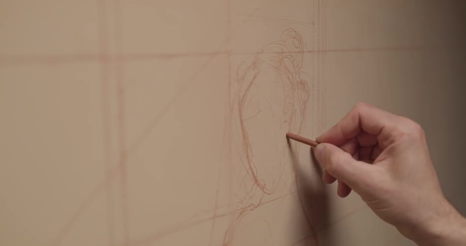 A man draws a face on a wall