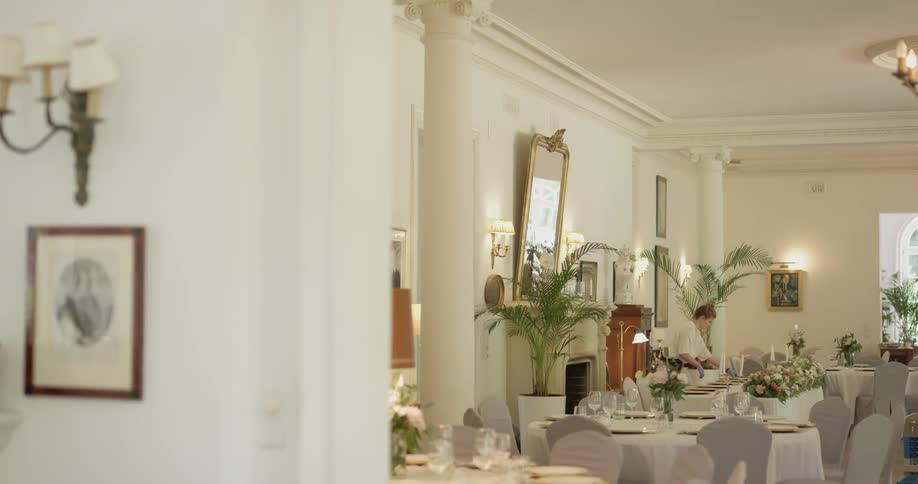 A woman setting a table in a formal restaurant