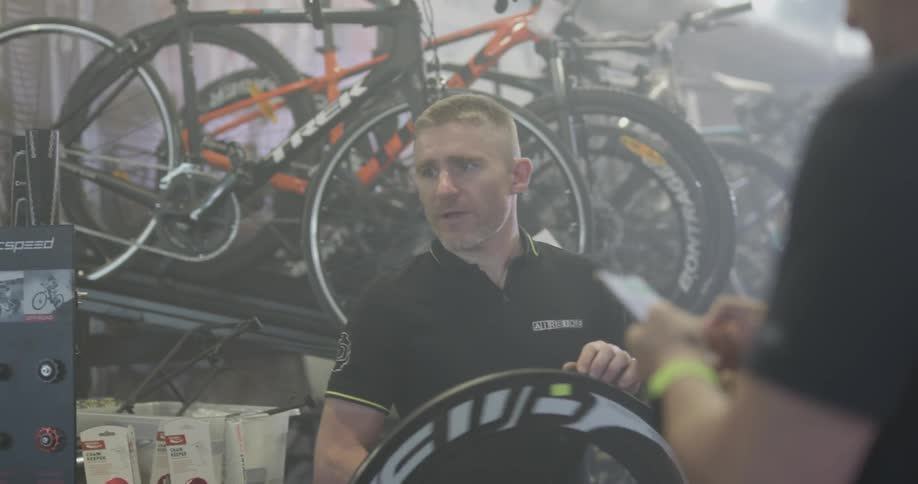 A man standing in front of several bikes on racks spins a bike tire
