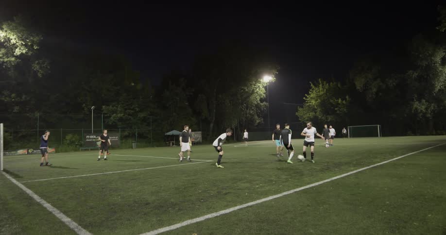 A group of men playing soccer at night